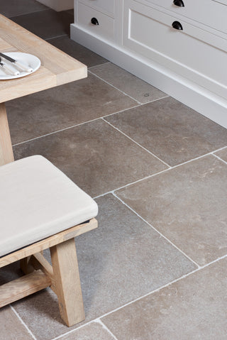 Limestone flooring tiles floor with a wooden bench and cushion in a kitchen setting