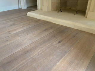 Wooden flooring in a room with a fireplace.