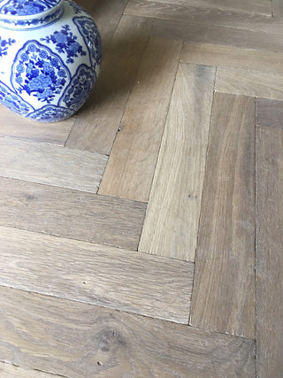 Wooden floor with herringbone pattern and a blue and white ceramic jar.