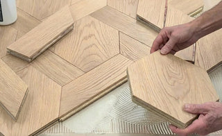 Hands assembling bespoke wood flooring with oak floorboards