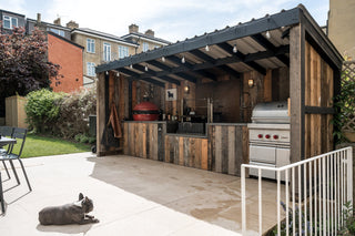 Outdoor kitchen with a stone patio, wooden pergola and grill area in a residential backyard