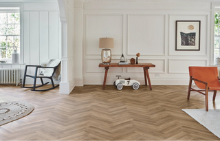 Living room with wooden herringbone floor, furniture, and decor.